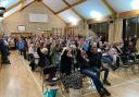 People at the meeting in Meifod raise their hands to object to the pylon proposal.