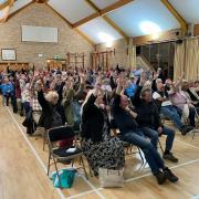 People at the meeting in Meifod raise their hands to object to the pylon proposal.