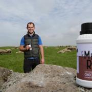 Dairy sheep farmer Huw Jones with the flavoured ewe's milk drinks and his flock at Ty'n Llan Farm ,Anglesey