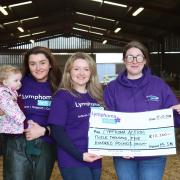 Sisters Jodie and Sophie with young niece Seren present a cheque to Laura from Lymphoma Action at the farm in Dolfor.